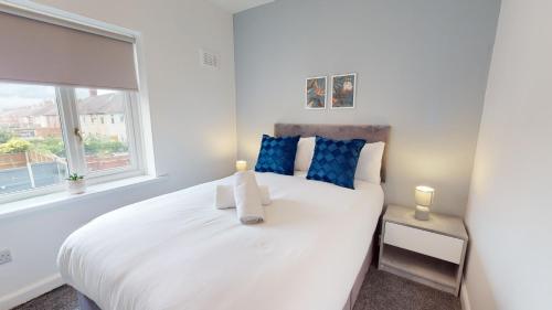 a bedroom with a white bed with blue pillows and a window at Stratford House Hartlepool Horizon Stays in Hartlepool