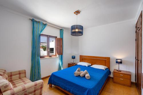 ein Schlafzimmer mit einem Bett mit zwei ausgestopften Tieren darauf in der Unterkunft Apartamentos Capitão by Umbral in Porto Covo