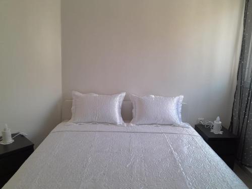 - une chambre avec un lit doté de draps et d'oreillers blancs dans l'établissement Bel appartement meublé à Temara 10 minutes de la plage et 15 minutes du stade Prince Moulay Abdellah, à Oulad Kerroum