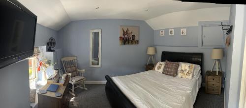 a bedroom with blue walls and a bed and a tv at The Crewe Arms in Hinton in the Hedges