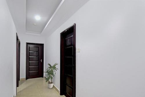 a hallway with a black door and a plant at OYO Flagship Dreamy Sunrise By Stayapart Near City Centre Salt Lake in Kolkata