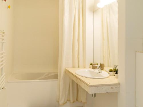 a white bathroom with a sink and a shower at Bright One-Bedroom Condo with Modern Amenities in Bucharest