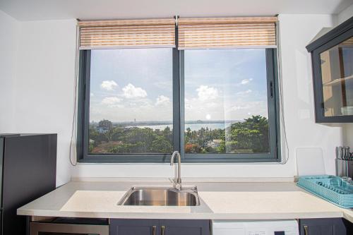 uma cozinha com um lavatório e 2 janelas grandes em Tanzanite Serviced Apartment - TSA Masaki em Dar es Salaam