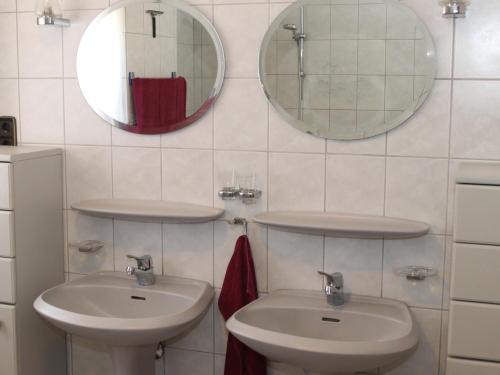 La salle de bains est pourvue de 2 lavabos et de miroirs sur le mur. dans l'établissement Ferienwohnung Marquis, à Bad Sobernheim