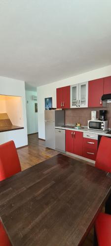 a kitchen with red cabinets and a wooden table at Apartments Mery in Supetar