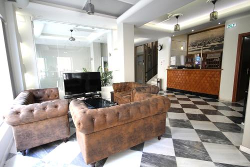 2 sillas de cuero y TV en el vestíbulo en Mirabello Hotel en Heraclión