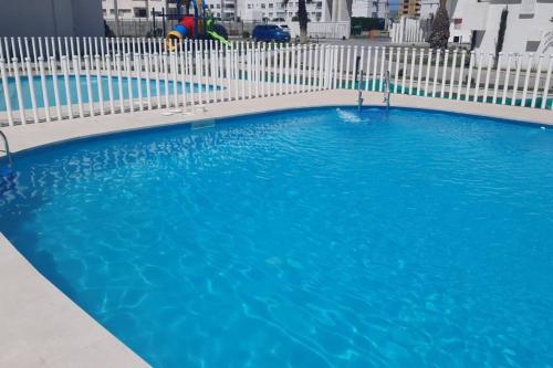 ein großer blauer Pool neben einem weißen Zaun in der Unterkunft Excelente departamento nuevo a pasos de la playa in La Serena