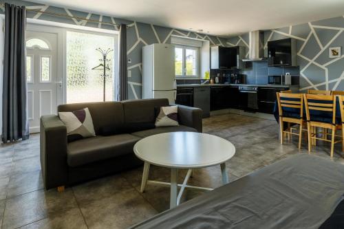 een woonkamer met een bank en een tafel bij Village house 3 bedrooms large terrace - Dodo et Tartine in Villedieu-les-Poëles