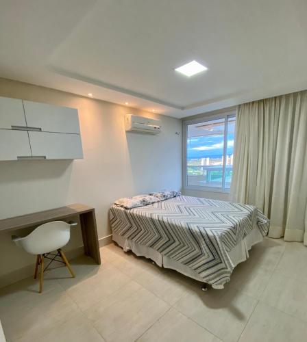 a bedroom with a bed and a desk and a window at Apartamento confortável, localização extra -recepção 24h- Varanda com vista panorâmica in Juazeiro do Norte