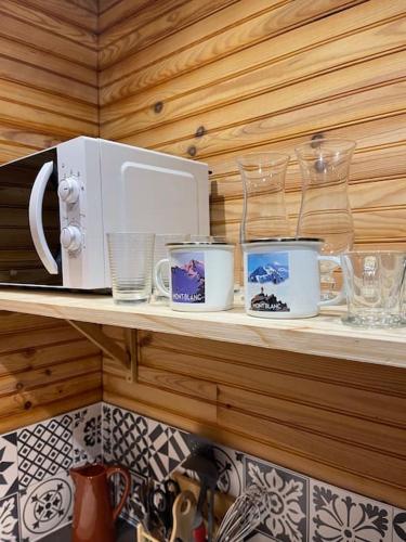 une étagère avec des tasses et des verres ainsi qu'un four micro-ondes dans l'établissement Romantique chalet avec sauna et jacuzzi extérieur, à Arthon