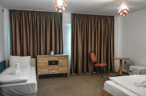 a hotel room with two beds and a desk and a chair at Hotel Atlantic Costinesti in Costinesti