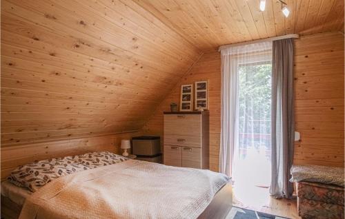 a bedroom with a bed in a wooden room with a window at Cozy Home In Morag With Lake View in Morąg