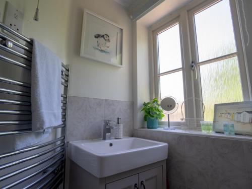 a bathroom with a white sink and a window at Pass the Keys Lovely 4 bedroom family home with garden parking in Cheltenham