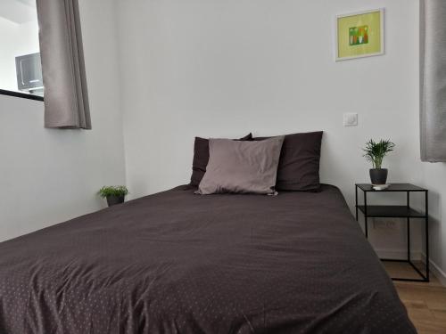 um quarto com uma cama com um cobertor cinzento em Le 4.01 proche centre em Lannion