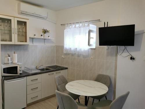 a kitchen with a table and chairs and a tv at Radunica Apartment in Split