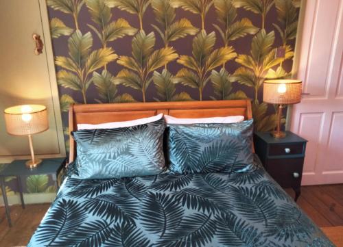 a bedroom with a bed with blue pillows and a wallpaper at Garden Cottage in Guisborough