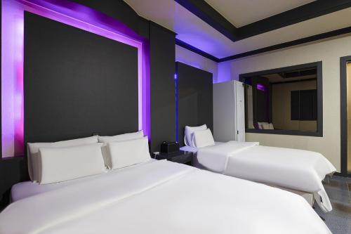 2 camas blancas en una habitación con luces moradas en Carlton Hotel en Incheon