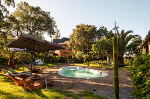 a swimming pool with chairs and an umbrella at Quinta dos Sarilhos in Pedrógão Grande