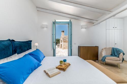 1 dormitorio con 1 cama grande con almohadas azules y silla en Trulli Ericla Resort, en Castellana Grotte