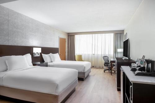a hotel room with two beds and a desk at Wyndham Indianapolis Airport in Indianapolis
