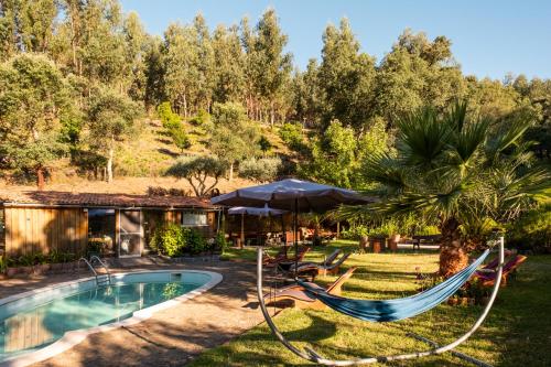 a backyard with a pool and hammocks and a house at Quinta dos Sarilhos in Pedrógão Grande