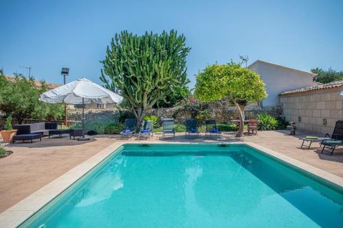 a swimming pool in a yard with chairs and an umbrella at Sa Barcella TI 64 in Sineu