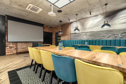 a conference room with a long table and yellow chairs at Stawa Villa & Apart in Świnoujście