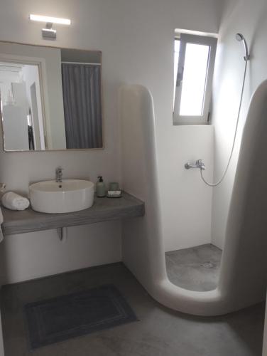 Baño blanco con lavabo y espejo en the South Breeze en Karistos