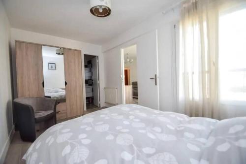 a white bedroom with a bed and a chair at 2 pièces tout confort à Alfortville - chez Christophe in Alfortville