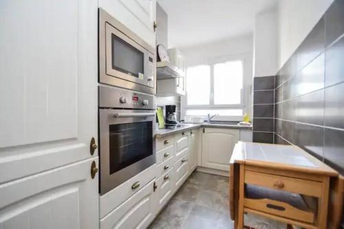 a kitchen with white cabinets and a tv on the wall at 2 pièces tout confort à Alfortville - chez Christophe in Alfortville