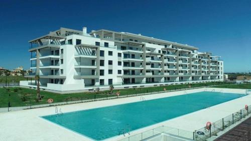 een groot wit appartementencomplex met een zwembad bij Malvagon Isla Canela los flamencos in Isla Canela