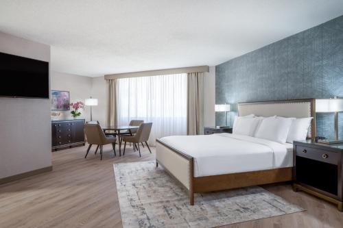 a hotel room with a bed and a dining room at Wyndham Indianapolis Airport in Indianapolis