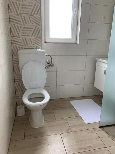 a bathroom with a white toilet and a window at Apartman TESA in Sanski most