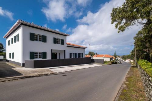 a white house on the side of a road at Batalha Family House in Fenais da Luz