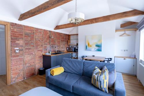 a living room with a blue couch and a brick wall at Apartment 6 at Number 8: City centre, 1 bedroom, sofa bed in lounge in Kent