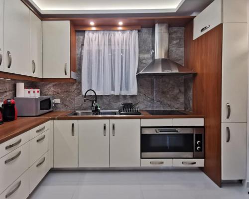 a kitchen with white cabinets and a sink and a microwave at Keti's home in Athens