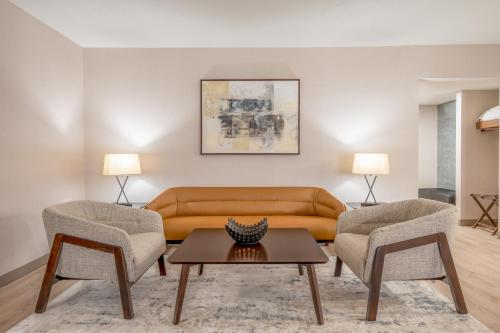 a living room with a couch and two chairs at Wyndham Indianapolis Airport in Indianapolis