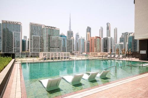a swimming pool with white chairs and a city skyline at The Suite Dubai 15 Northside Luxury Living in Dubai