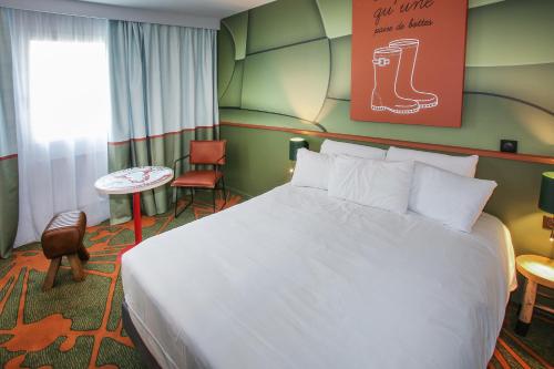 a hotel room with a large bed and a table at Ibis Styles Lisieux Normandie in Lisieux