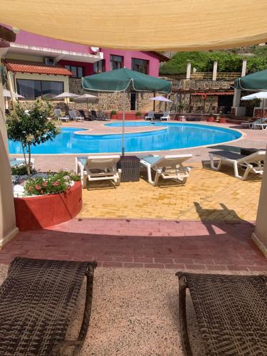 a large swimming pool with chairs and umbrellas at Hotel Loggas in Sidhirokhórion