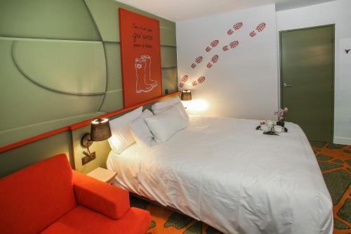 a bedroom with a bed and a red chair at Ibis Styles Lisieux Normandie in Lisieux