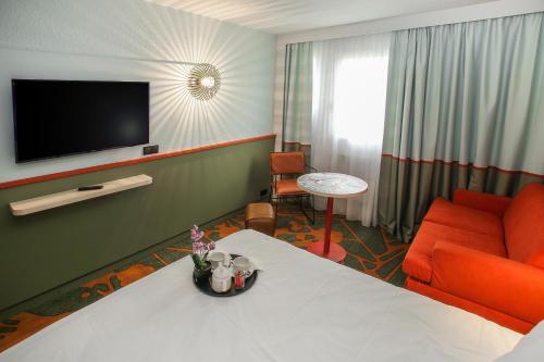a hotel room with a couch and a television at Ibis Styles Lisieux Normandie in Lisieux
