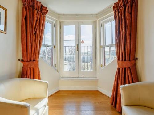a living room with two chairs and two windows at Craiglea Lodge & Barn in Latheron