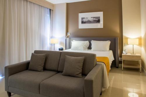 a hotel room with a bed and a couch at Linda suíte de hotel Harry in Rio de Janeiro