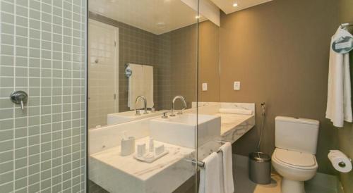 a bathroom with two sinks and a toilet and a mirror at Linda suíte de hotel Harry in Rio de Janeiro