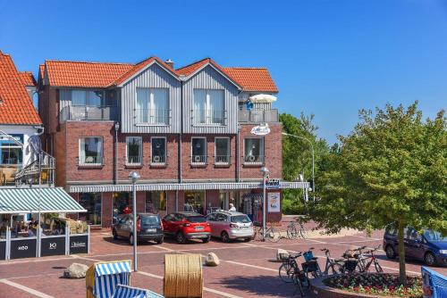 a large brick building with cars parked in a parking lot at Haus Hafenblick in Bensersiel