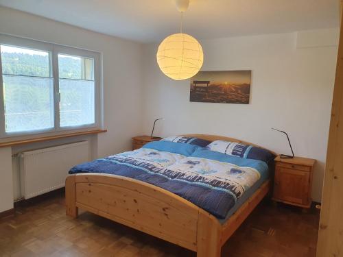 ein Schlafzimmer mit einem Bett und einer Hängeleuchte in der Unterkunft Les petits Rosiers in Tramelan