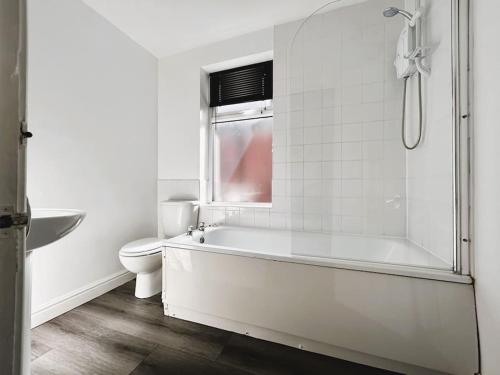 a white bathroom with a tub and a toilet at Salisbury Place by SG Property Group in Crewe