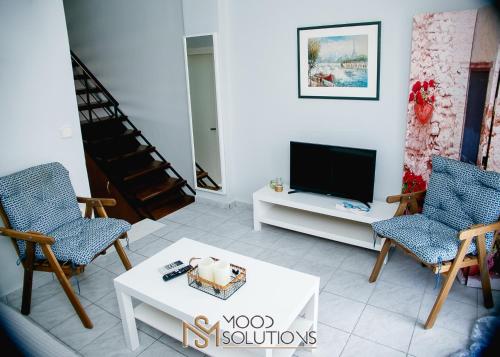 a living room with a tv and two chairs and a table at Dryades Pefkochori MoodSolutions Living in Pefkohori