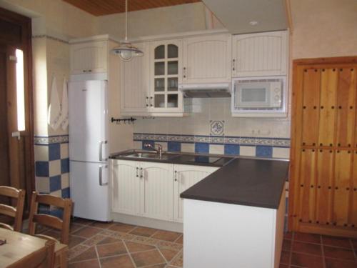 una cucina con mobili bianchi e un frigorifero bianco di La Plazuela a Morcuera